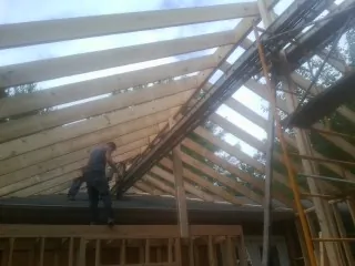 Rafters going up over a new addition with a worker on the wall in Conway